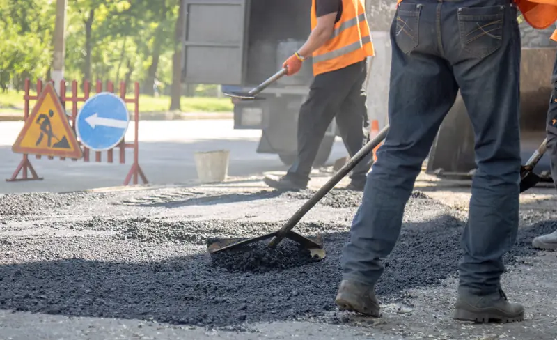 Trabajadores en obra vial con jean de dotación, botas y chaleco reflectivo
